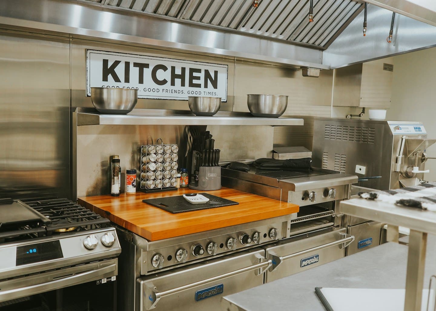 Elettrodomestici professionali da cucina e un piano di lavoro in legno con utensili.